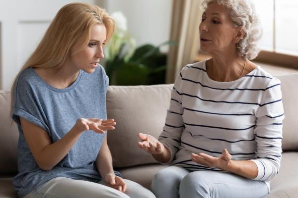 Stressed young blo<em></em>nde grown up daughter arguing with nervous old mature mother, sitting together at home. Irritated elderly woman lecturing adult child, different generations misunderstanding gap.