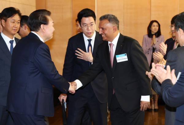 S-Oil CEO Anwar A. Al-Hejazi (right) shakes hands with President Yoon Suk Yeol at the presidential meeting with foreign-invested company representatives and heads of Seoul-ba<em></em>sed commerce chambers in Seoul on Wednesday. (Yonhap)